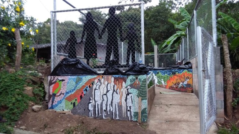 Vista general del monumento en memoria de las víctimas de la masacre de La Joya, que incluye: un muro de concreto con placas de granito negro, una escultura con siluetas que representan a las familias víctimas y dos murales de mosaicos. Crédito: Johanna Marroquín.